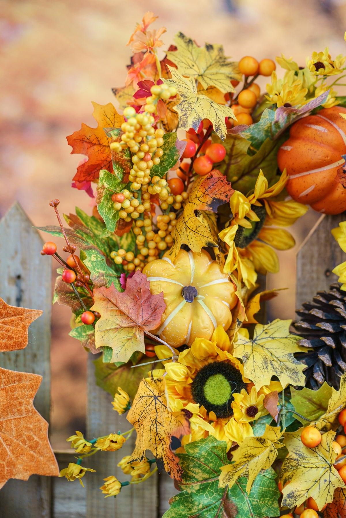 Détail d'une couronne d'automne : tournesols, petites citrouilles, baies et feuilles d'érable