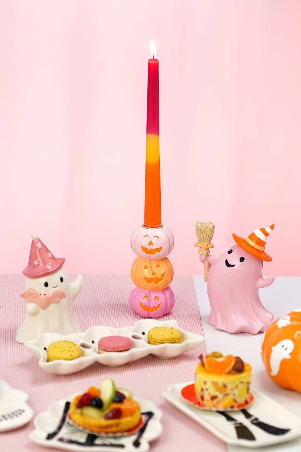 Bougeoir à trois citrouilles souriantes sur une table de goûter d'Halloween avec fantômes pastel