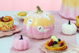 Citrouille Halloween dégradé pêche et rose ornée de fantômes, en scène sur une table pastel d'Halloween