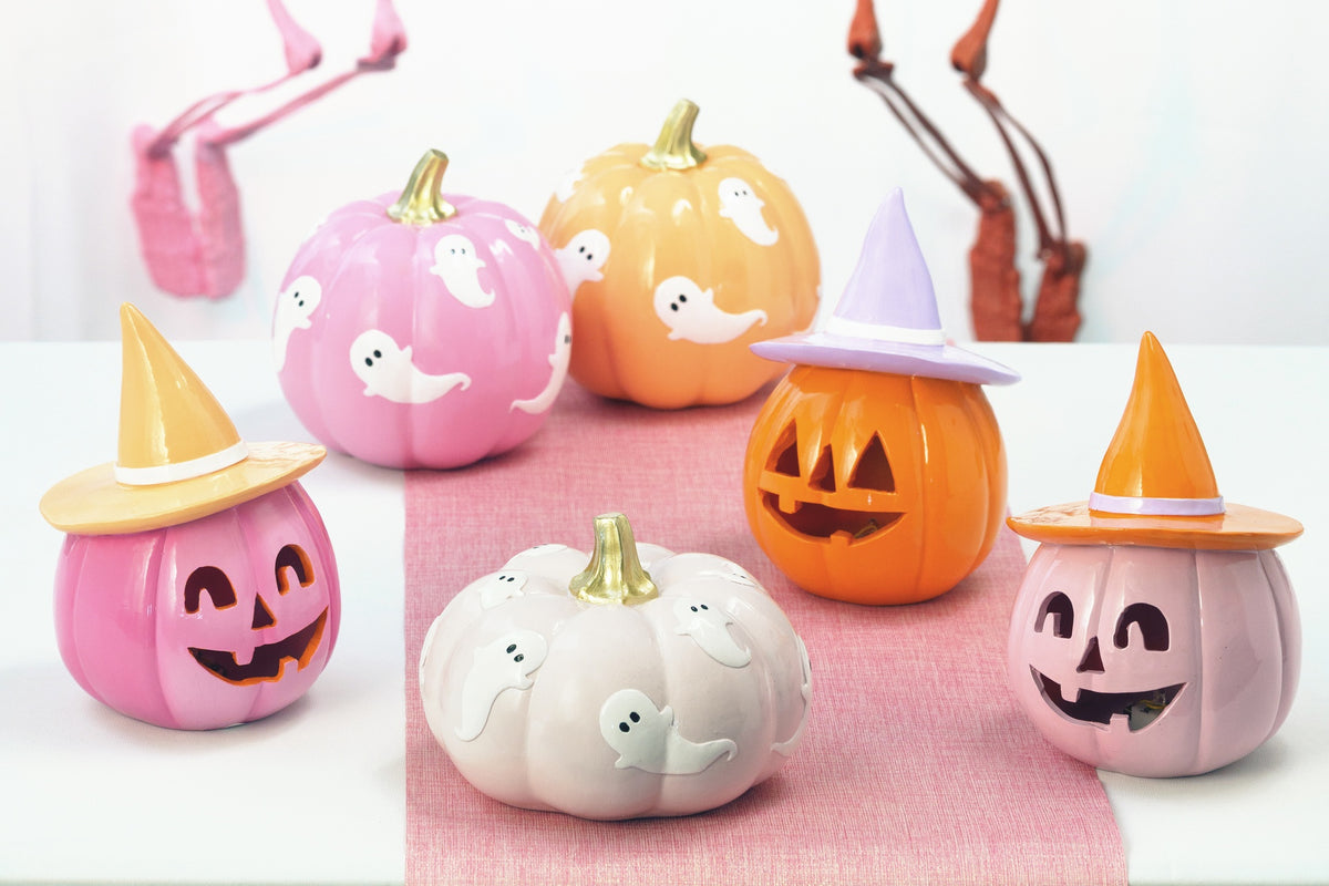 Citrouilles Halloween pastel à chapeaux de sorcière disposées sur un chemin de table rose, ambiance d'Halloween