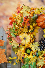 Détail d'une couronne d'automne : tournesols, petites citrouilles, baies et feuilles d'érable