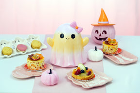 Fantôme Halloween souriant en dégradé jaune et rose à nœud rose, sur une table de goûter d'Halloween