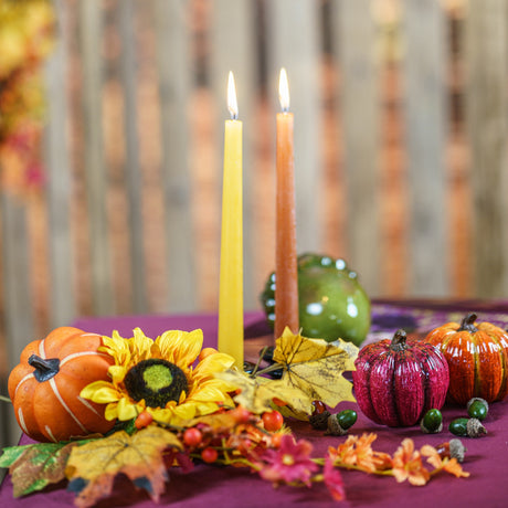 Composition d'automne de tournesols, citrouilles et feuilles autour de bougies sur une table d'automne