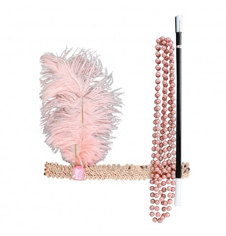 The image shows a Charleston-themed party kit in a vintage pink color, consisting of three pieces: a feathered headband, a long pearl necklace, and a cigarette holder, all styled to evoke the 1920s flapper era.